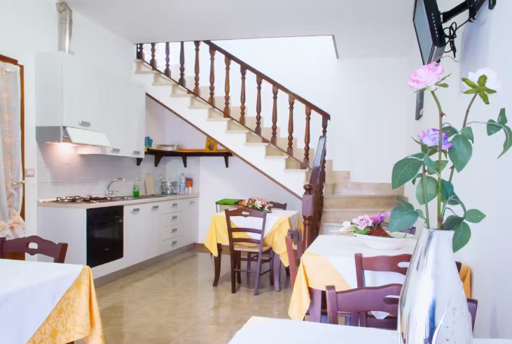 Soggiorno di Casa Pianalto con angolo cottura, tavolo da pranzo e scala che conduce alle camere